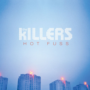 Album cover of 'Hot Fuss' by The Killers featuring a blue sky background and illuminated buildings.